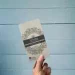 a hand holding a BeHappy Vegan White Choc 85g in packaging, with a blue background