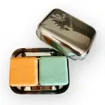 An open BentoNinja Travel Case Soap Stainless Steel, with two bars of soap. On the left is an orange bar and on the right is a green bar.