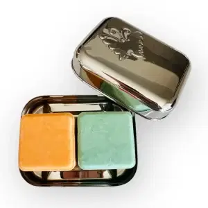 An open BentoNinja Travel Case Soap Stainless Steel, with two bars of soap. On the left is an orange bar and on the right is a green bar.