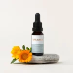 Bottler of Herb Farm Bakuchiol Face Oil 20ml sitting on a stone with some flowers next to it