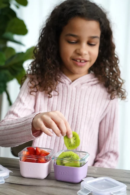 Girl pulling a kiwi slice for one of the Melii glass containers