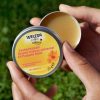 Hands holding an open container of Weleda Calendula All Purpose Balm 25g