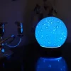Zurma Diffuser Moon on a table in the dark with the internal light turned on, so it looks like a blue moon.
