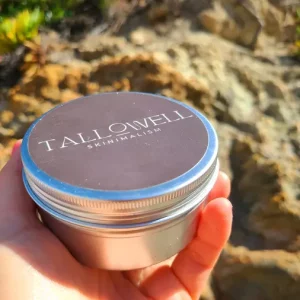 a hand holding a tin of Tallowwell Bare Balm