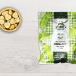 A bag of Bostock Butterfly Chicken Dill Lemon on a table with a bowl of pickles next to it.