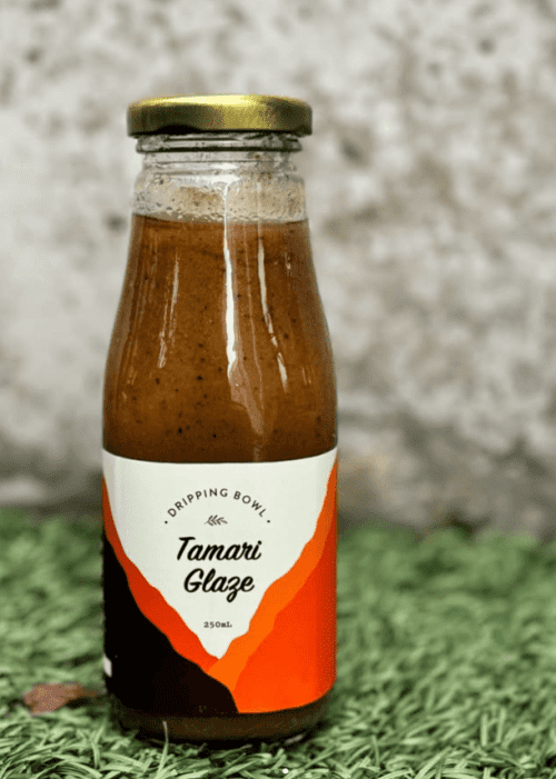a bottle of DrippingBowl Tamari Glaze 250ml sitting on grass