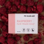 TradeAid Soap Raspberry 80g on a table surrounded by raspberries