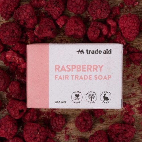 TradeAid Soap Raspberry 80g on a table surrounded by raspberries