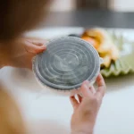 Hands holding a container that has a CaliWoods Silicone Stretch Lid Large on it