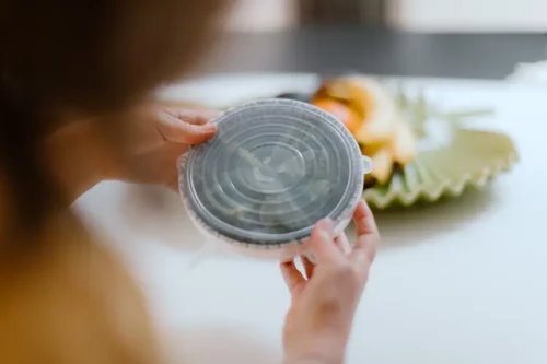 Hands holding a container that has a CaliWoods Silicone Stretch Lid Large on it