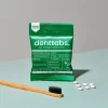 Denttabs Tooth Tablets Mint Fluoride Free packaging with a few tablets and a bamboo toothbrush next to it
