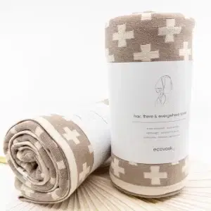 two Ecovask Hair Travel Towel Hummus Chevron rolled up in their packaging laying on a table