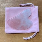 VeganStore Gua Sha Rose Quartz on top of a pink velvet like pouch