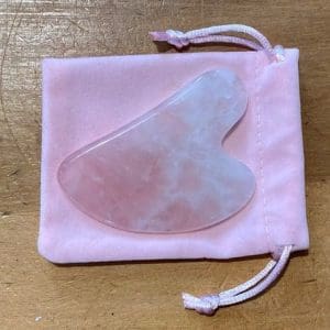 VeganStore Gua Sha Rose Quartz on top of a pink velvet like pouch