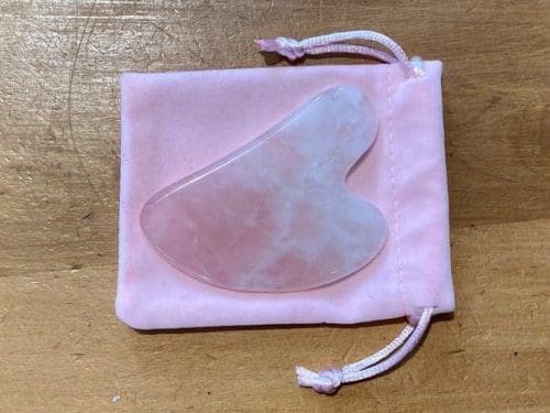 VeganStore Gua Sha Rose Quartz on top of a pink velvet like pouch